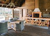 Обеденный стол и кирпичное барбекю на крытой террасе для отдыха, между основным домом и банным комплексом